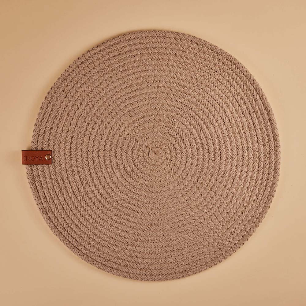 Round fabric placemat with a leather tag on a beige background