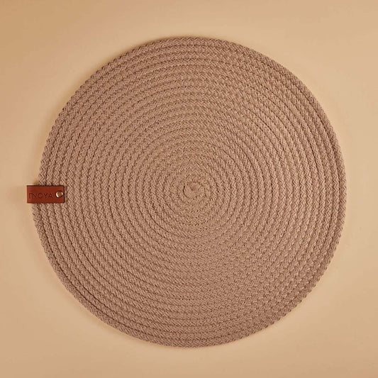 Round fabric placemat with a leather tag on a beige background