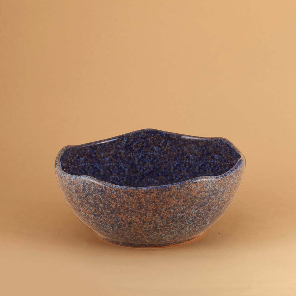 Blue Stardust ceramic bowl with blue speckled glaze on a beige background