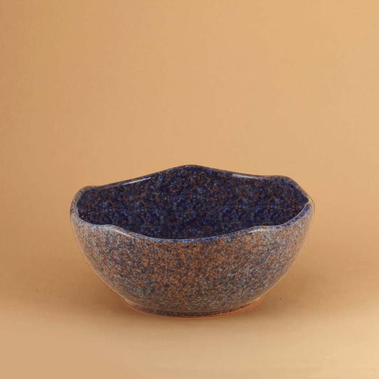 Blue Stardust ceramic bowl with blue speckled glaze on a beige background
