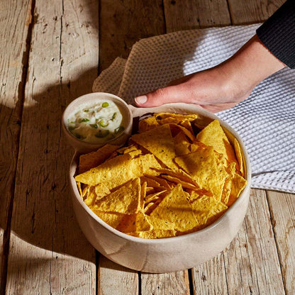 Chip and dip bowl of tortilla chips with a side of guacamole on a wooden surface