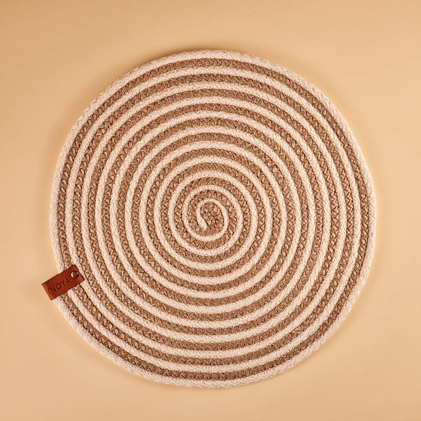 A beige and brown spiral fabric placemat.
