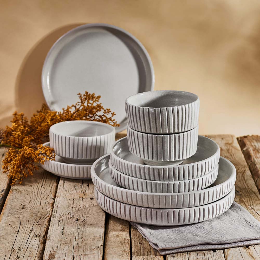 Set of gray ceramic dishes on a wooden table with a warm background