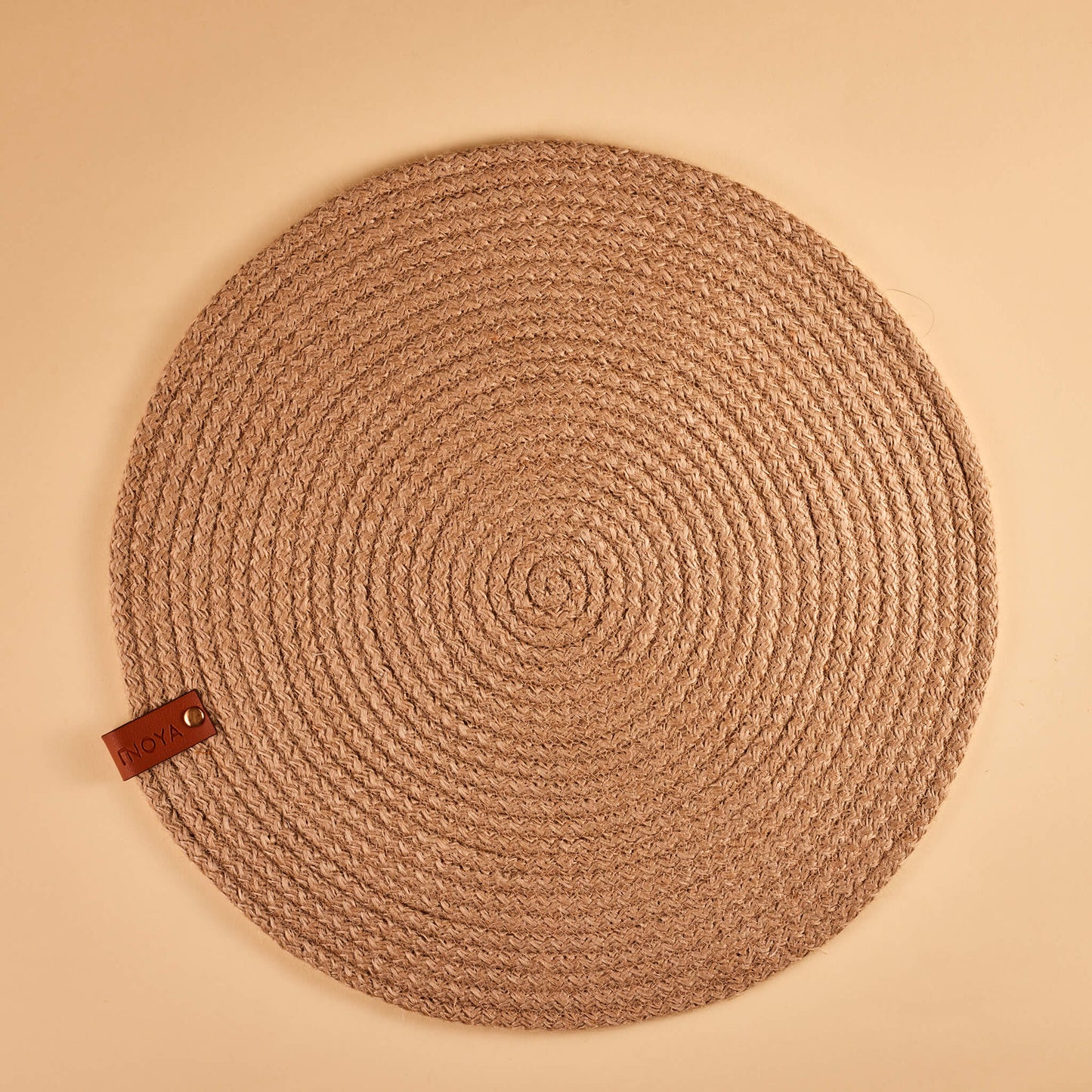 A round beige jute placemat on a plain background.