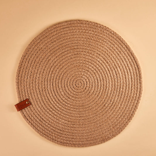 A round beige jute placemat on a plain background.