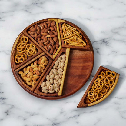 Wooden snack platter filled with nuts and pretzels on a marble countertop.