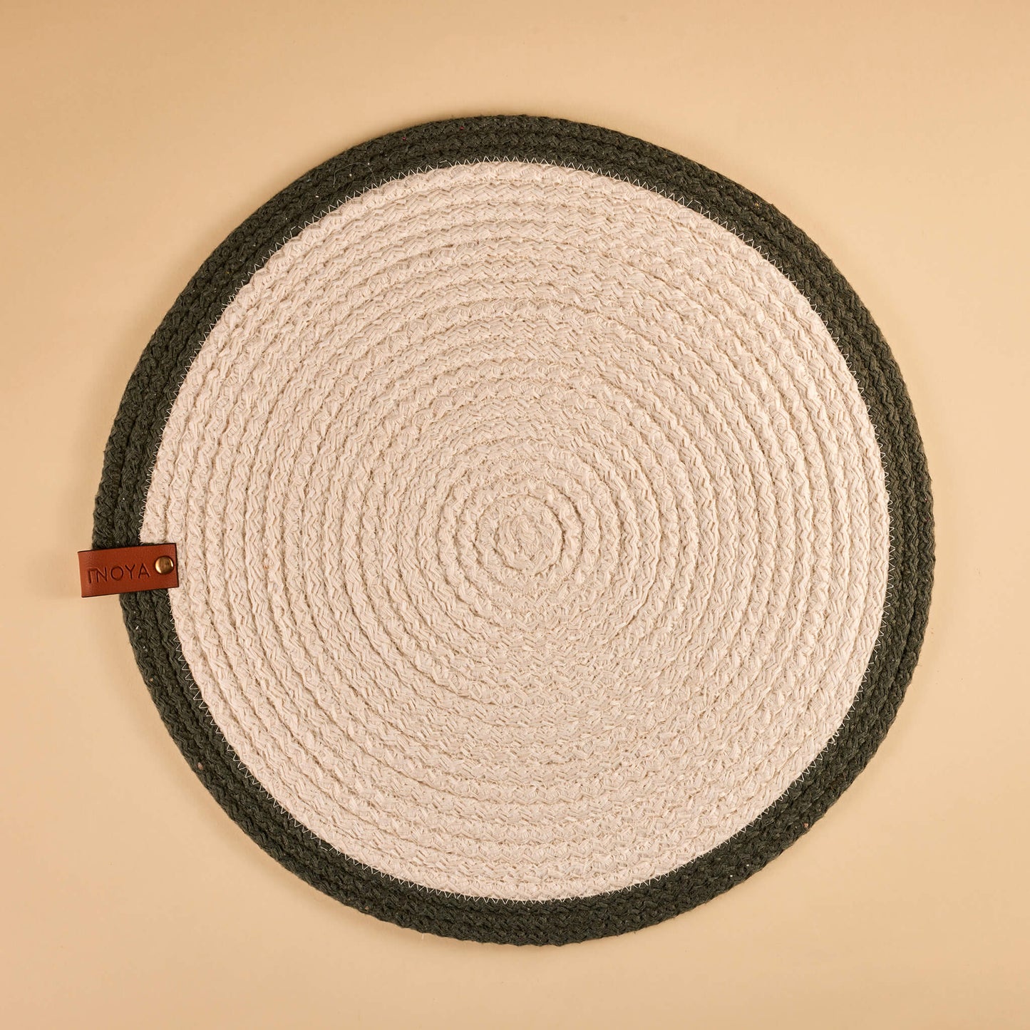 A round fabric placemat with a white center and olive border.