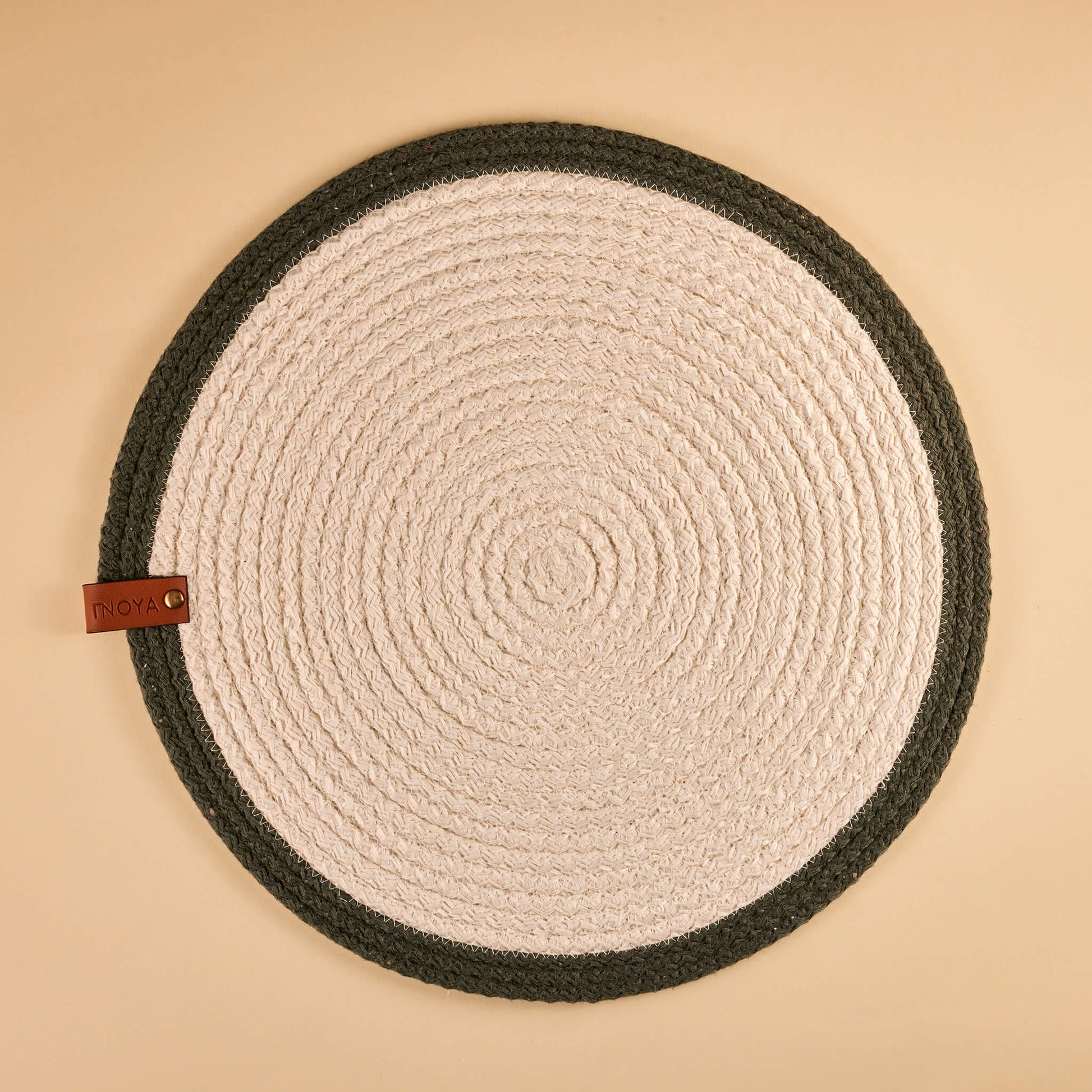 A round fabric placemat with a white center and olive border.