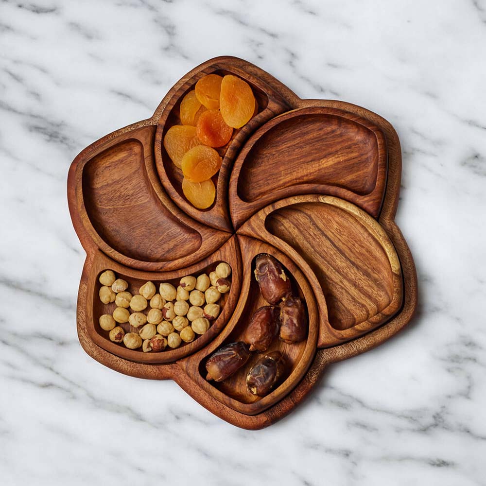 Wooden tray containing dried fruits and nuts on a marble countertop.