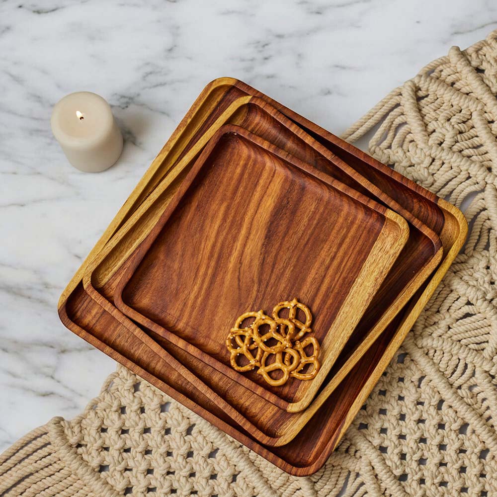 Set of wooden trays with a decorative pattern on a textured placemat.