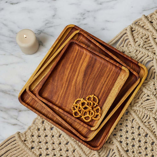 Set of wooden trays with a decorative pattern on a textured placemat.