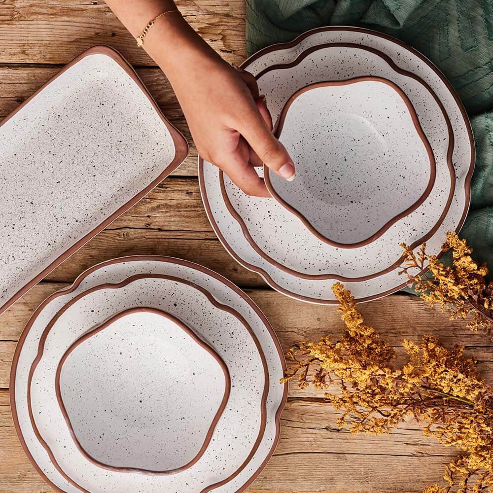 Speckled ceramic plates with brown rims on a wooden surface.