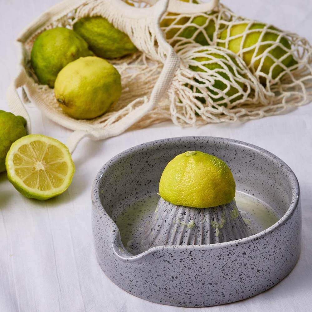 Gray ceramic lemon squeezer with lemons on a white background