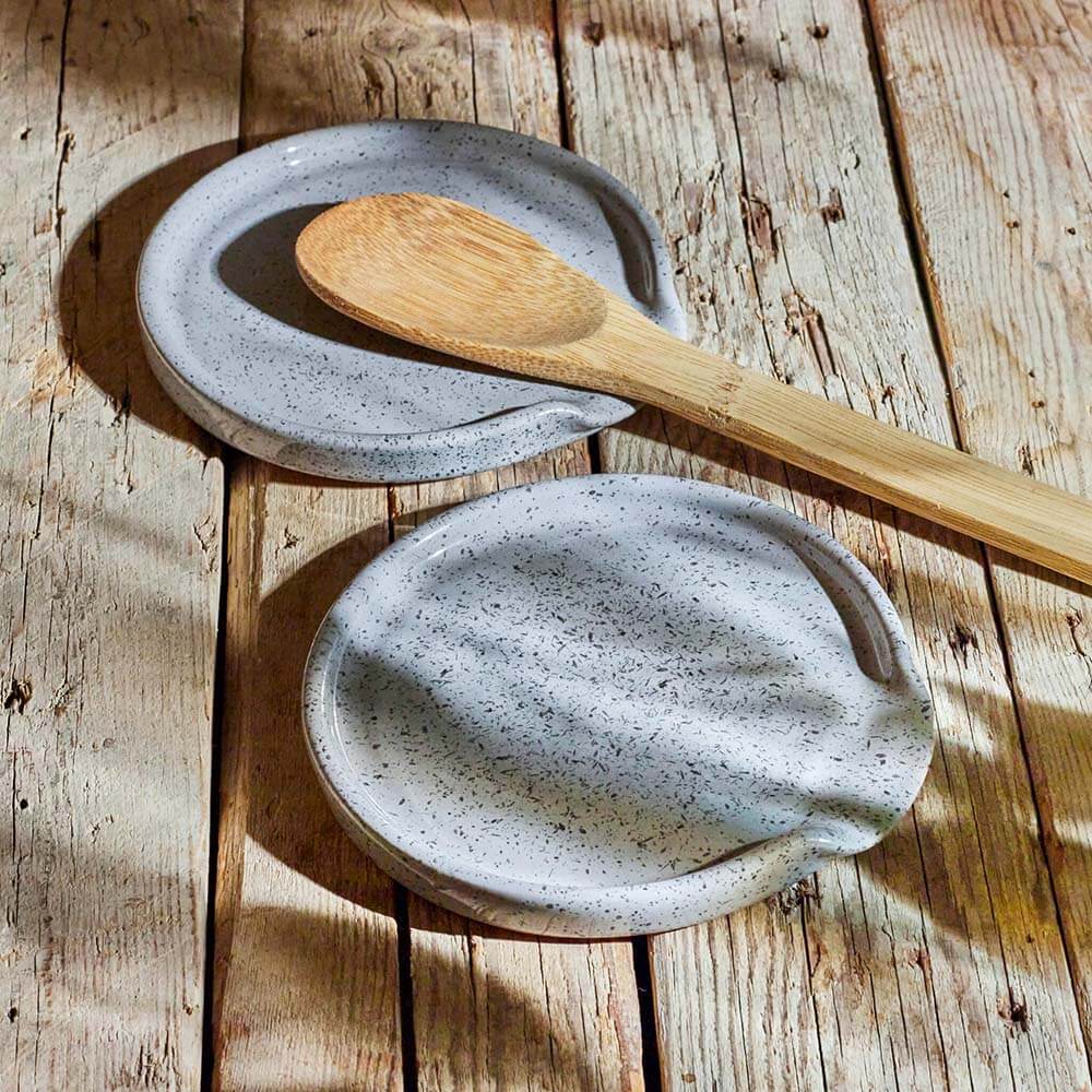 ceramic spoon rest with a wooden spoon on a wooden surface
