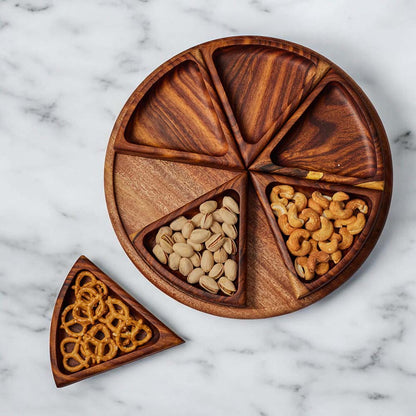 Wooden snack platter filled with nuts and pretzels on a marble countertop.
