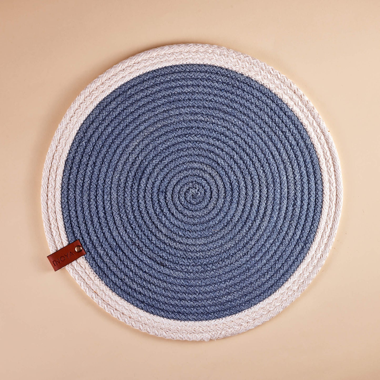A round placemat with a white border and blue circular pattern in the center.