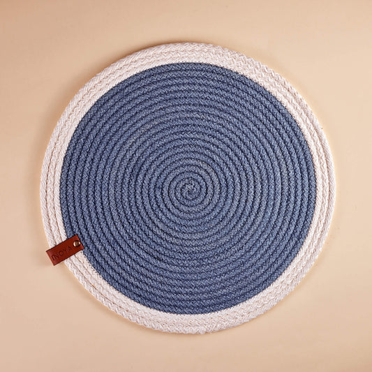 A round placemat with a white border and blue circular pattern in the center.
