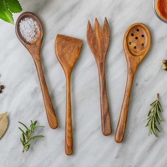 Set of wooden cooking utensils on a marble surface with herbs and spices.